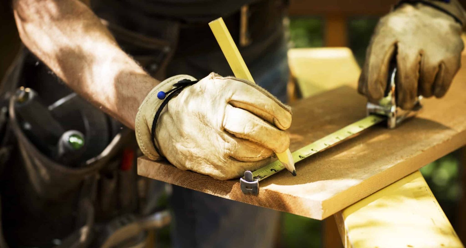 Carpenter Measuring A Wooden Plank. Closeup of carpenter marking lumber to saw.